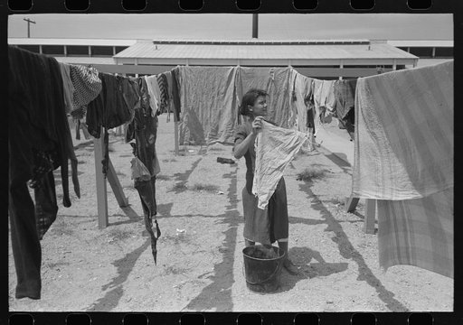 Wife of migratory worker hanging up laundry at the Agua Fria Migratory Labor Camp, Arizona