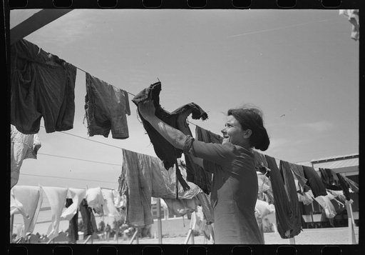 Untitled photo, possibly related to: Wife of migratory worker hanging up laundry at the Agua Fria Migratory Labor Camp, Arizona