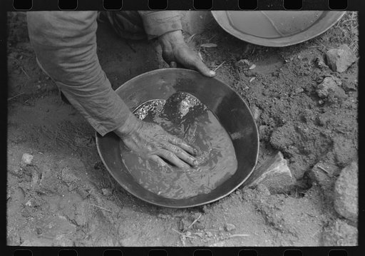 Pan of slush taken from "rocker." This pan will be rotated slowly with the hands, the waste thrown away as the gold sinks to the bottom until only the fine dirt and gold and little water remain. Pinos Altos, New Mexico