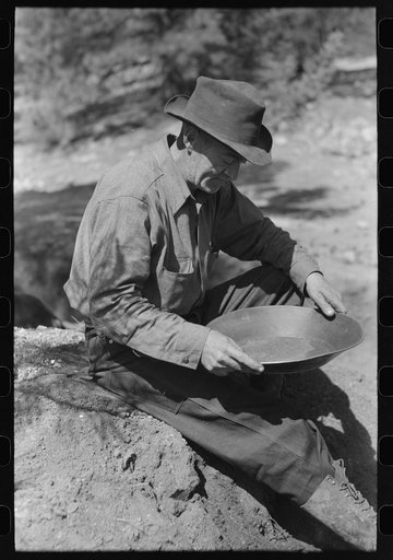 Gold prospector examining a pan to see how much gold it contains. Pinos Altos, New Mexico