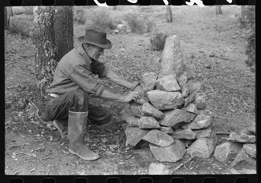 Prospector putting tin can containing his claim deed into his monument on his claim. Pinos Altos, New Mexico