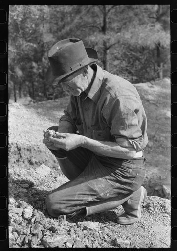 Prospector examining a piece of rock, Pinos Altos, New Mexico