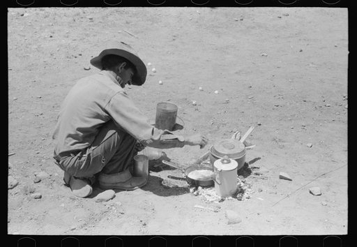 Faro Caudill frying eggs over camp fire the day he was moving his dugout. Pie Town, New Mexico