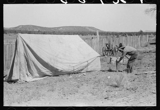 Faro Caudill driving tent posts; the family will live in the tent while the dugout is being rebuilt. Pie Town, New Mexico
