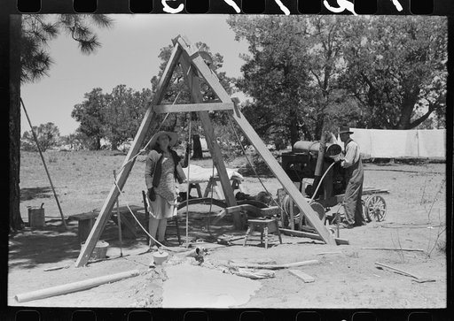 Untitled photo, possibly related to: Woman guiding the drilling tool for water well drilling. Pie Town, New Mexico