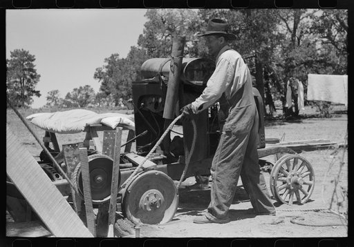 Untitled photo, possibly related to: Farmer drilling water well. In this picture he is loosening and tightening rope around the pulley, thus raising and lowering the drilling tool. Pie Town, New Mexico
