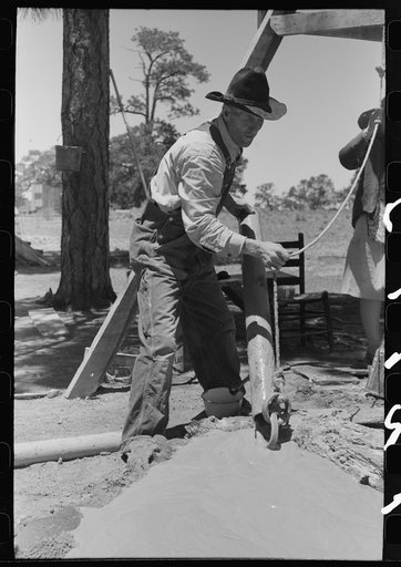 Farmer emptying slush from well which he is drilling with cable tools. Pie Town, New Mexico