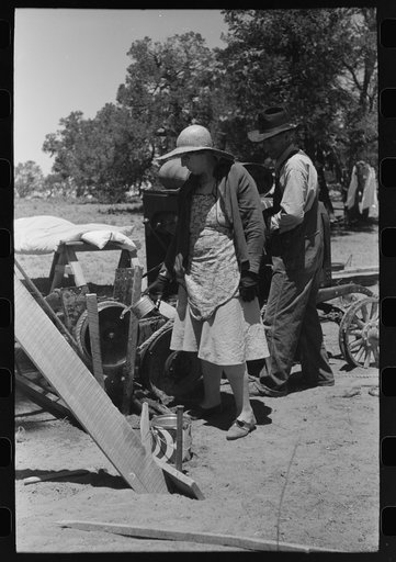 Pouring water on rope and pulley to cool them off while drilling water well with cable tools. Pie Town, New Mexico