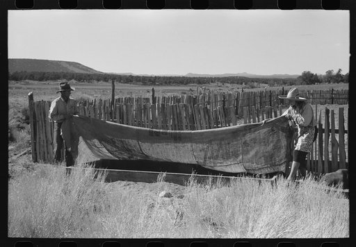 Faro and Doris Caudill covering up frame garden; large garden is in the background. Pie Town, New Mexico