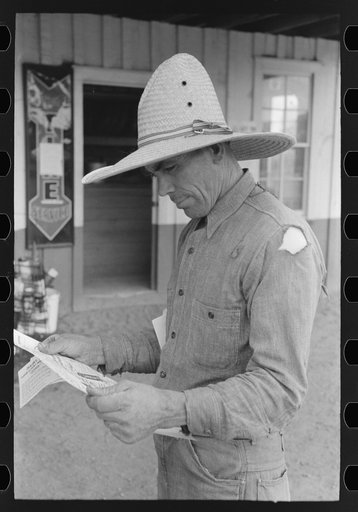 Mr. Leatherman studies some literature on electric fencing. Pie Town, New Mexico