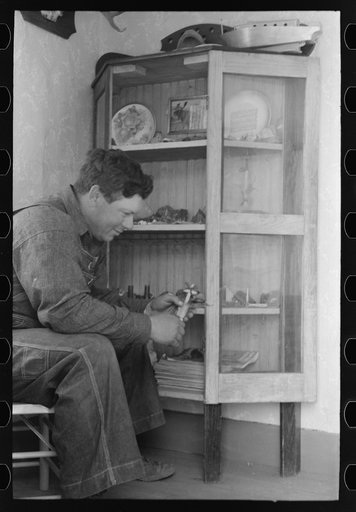 George Hutton, Jr. examines fetish used in Indian cermonies. He has a collection of rocks, curios, and Indian relics which is highly prized by the entire family. Pie Town, New Mexico