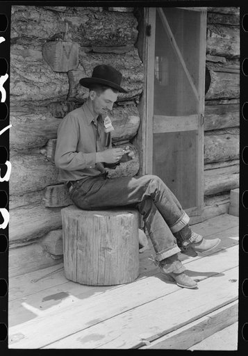 Farmer rolling a cigarette. Construction of log house is shown. This farmer rents farm and house from the man who homesteaded the place but is now unable to farm. Pie Town, New Mexico