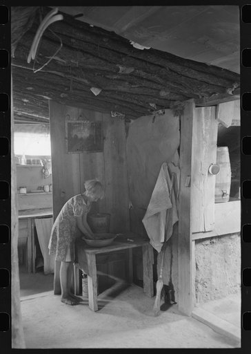 Jack Whinery's daughter washing her hands. This picture was taken in the dugout with natural lighting.  Notice the water cooler in cooling room at right. This cooling room is built cellar-like into the ground. Pie Town, New Mexico