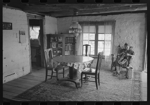 Untitled photo, possibly related to: Wife of homesteader working in dining room of her new adobe house. The lamp-chandelier above dining table was brought by her grandmother to Iowa when she homesteaded there. Pie Town, New Mexico