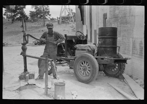 Untitled photo, possibly related to: Homesteader pumping water which he will haul home from town. Wells require cash to drill and some farmers have not yet been able to drill their own wells. Pie Town, New Mexico