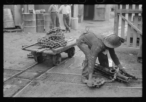 Miner picking up drilling equipment to put on truck, Mogollon, New Mexico