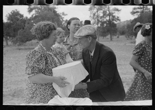 Mrs. Stagg handing pan of food to Mr. Stagg to put on the table at dinner of all day community sing. Pie Town, New Mexico