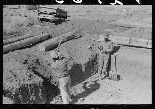 John Adams, a neighbor, is digging steps of the dugout while Faro Caudill takes time out for a cigarette. Pie Town, New Mexico