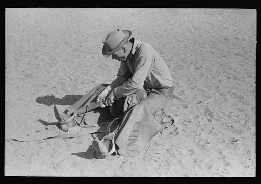 Cowboy testing stirrups at rodeo before broncbusting. Quemado, New Mexico