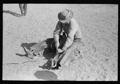 Cowboy testing stirrups at rodeo before broncbusting, Quemado, Mew Mexico