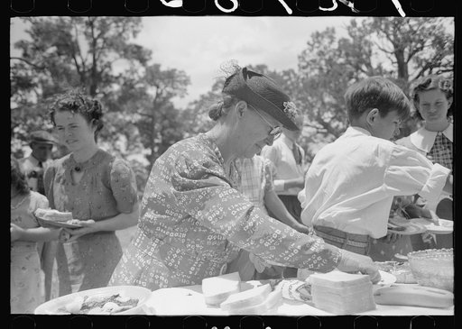 Farm woman arranging food on table at dinner during all day community sing, Pie Town, New Mexico