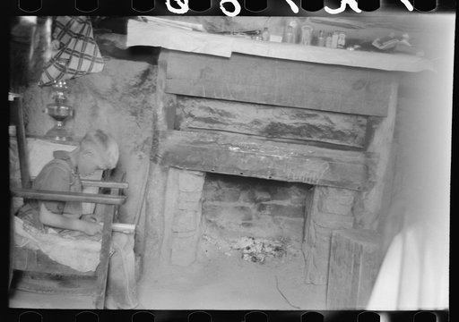 Untitled photo, possibly related to: Mr. Leatherman's son reading in front of fireplace in dugout, Pie Town, New Mexico