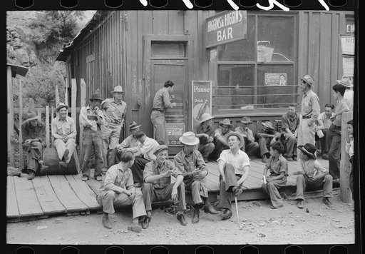 Untitled photo, possibly related to: Crowd of men sitting on board walk in front of bar at Mogollon, New Mexico, gold mining town