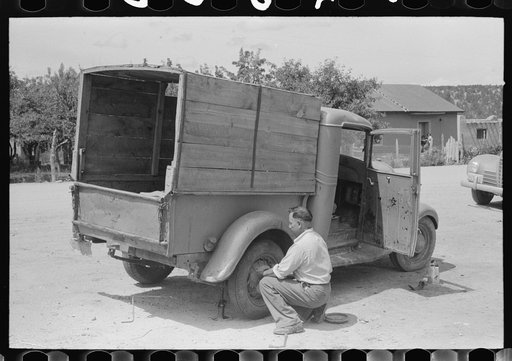 Merchant changing tire on his truck, Penasco, New Mexico