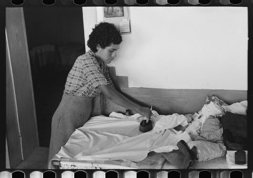 Daughter of Spanish-American farmer ironing. Chamisal, New Mexico