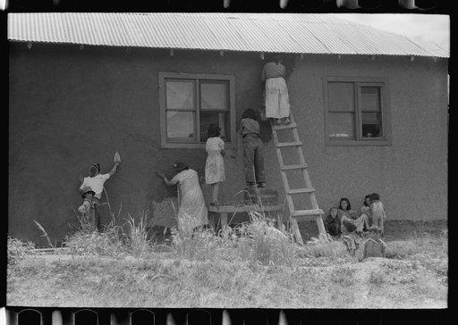 General view of plastering adobe house, Chamisal, New Mexico