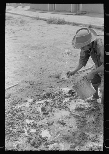 Spanish-American man adding water to plaster, Chamisal, New Mexico