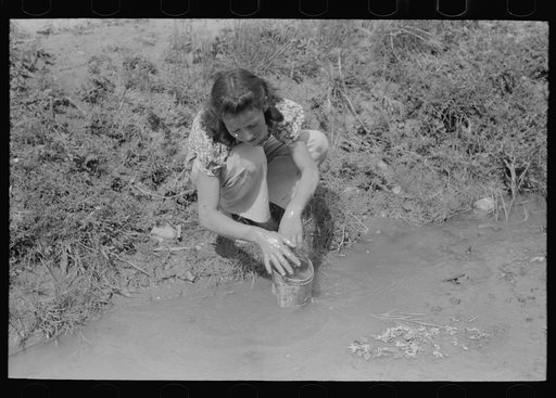 Spanish-American woman washing in irrigation ditch, Chamisal, New Mexico