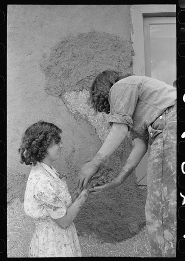Spanish-American women plastering an adobe house, Chamisal, New Mexico