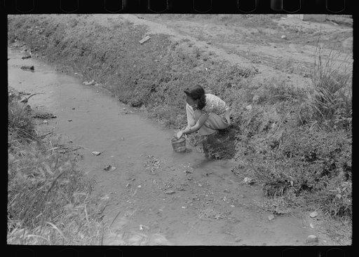 Washing in irrigation ditch, Chamisal, New Mexico