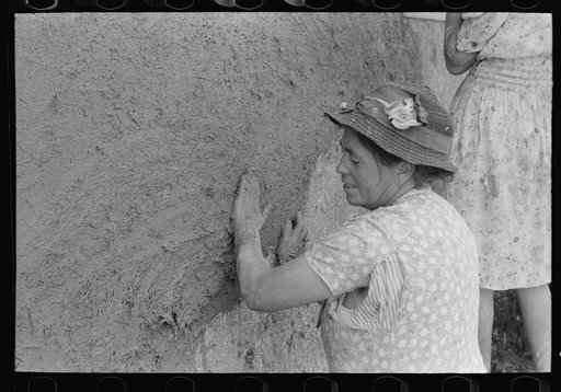 After plaster is applied with towel it is smoothed out with the hands. The women pride themselves on careful plastering, Chamisal, New Mexico