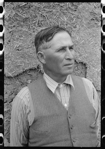 Untitled photo, possibly related to: Spanish-American farmer standing in front of adobe wall, Chamisal, New Mexico