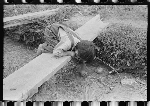 Spanish-American boy playing in irrigation ditch, Chamisal, New Mexico
