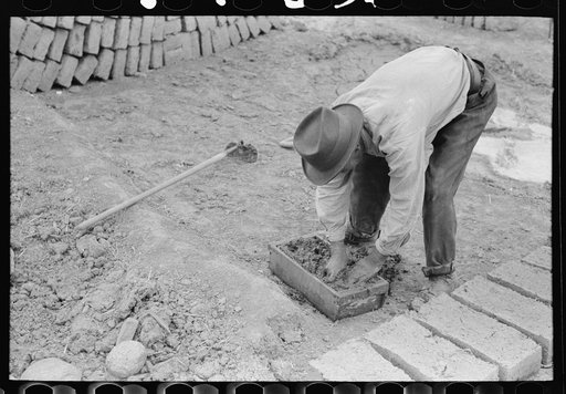 Untitled photo, possibly related to: Wooden form is placed over adobe mixture in making bricks, Chamisal, New Mexico
