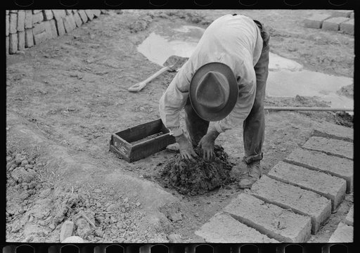 Mixing adobe for making bricks, Chamisal, New Mexico