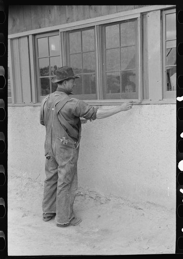 Spanish-American farmer painting window frames on his house. Spanish-American are proud of their houses. They are kept in excellent repair. Chamisal, New Mexico