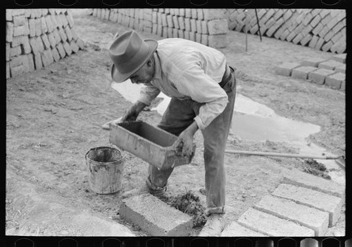 Spanish-American removing form shaped adobe brick. The adobe brick is next dried by the sun. Chamisal, New Mexico