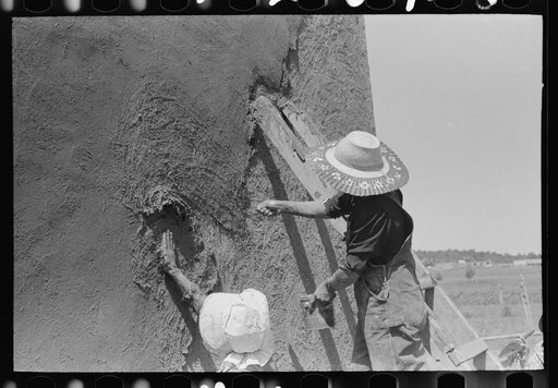 Spanish-American women plastering adobe house, Chamisal, New Mexico