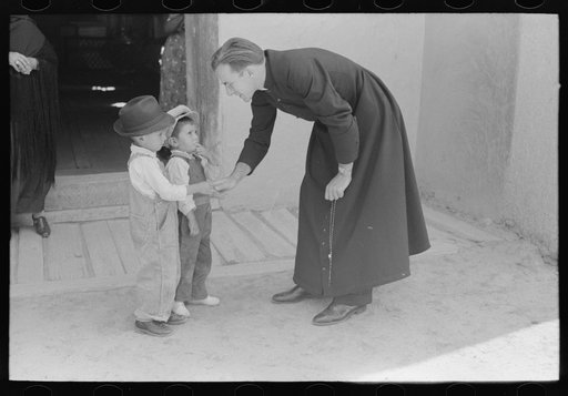 Catholic priest greeting small Spanish-American boy after Mass. Trampas, New Mexico