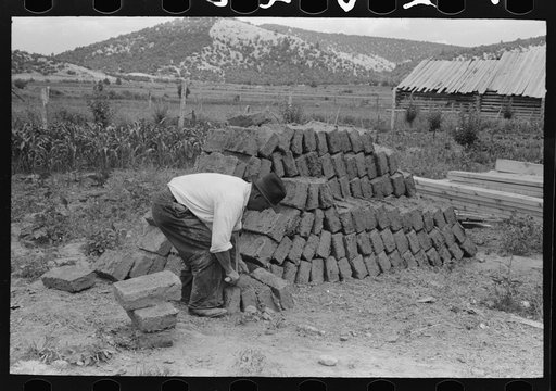 Adobe bricks, shaving one down to size, Penasco, New Mexico