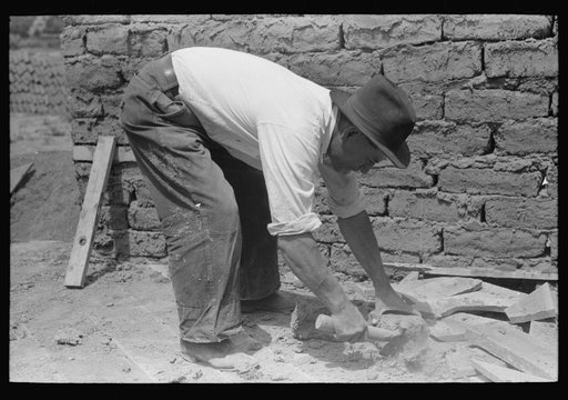 An ordinary hatchet is used to chip adobe bricks used in house construction, Penasco, New Mexico