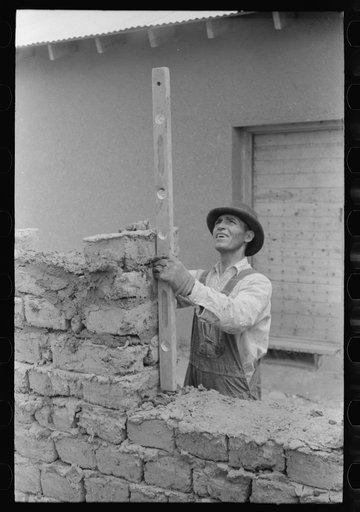 Using a level in constructing a window opening of an adobe house. Penasco, New Mexico