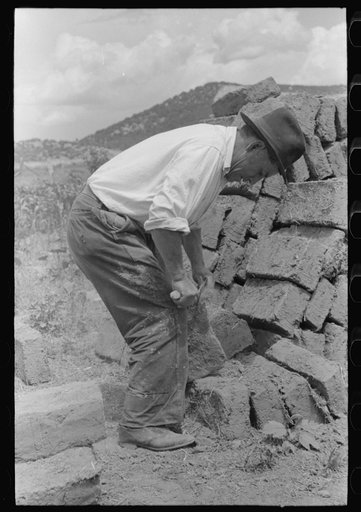 Removing the rough edges from adobe bricks with trowel, Penasco, New Mexico