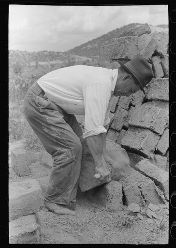 Removing the rough edges from adobe bricks with a trowel, Penasco, New Mexico