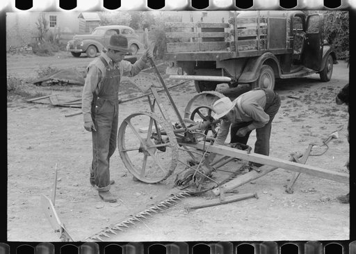 Spanish-American men looking over a mower, Chamisal, New Mexico