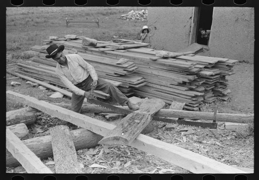 Son of Spanish-American farmer sawing slabs of wood to size for use in roof construction, Amalia, New Mexico